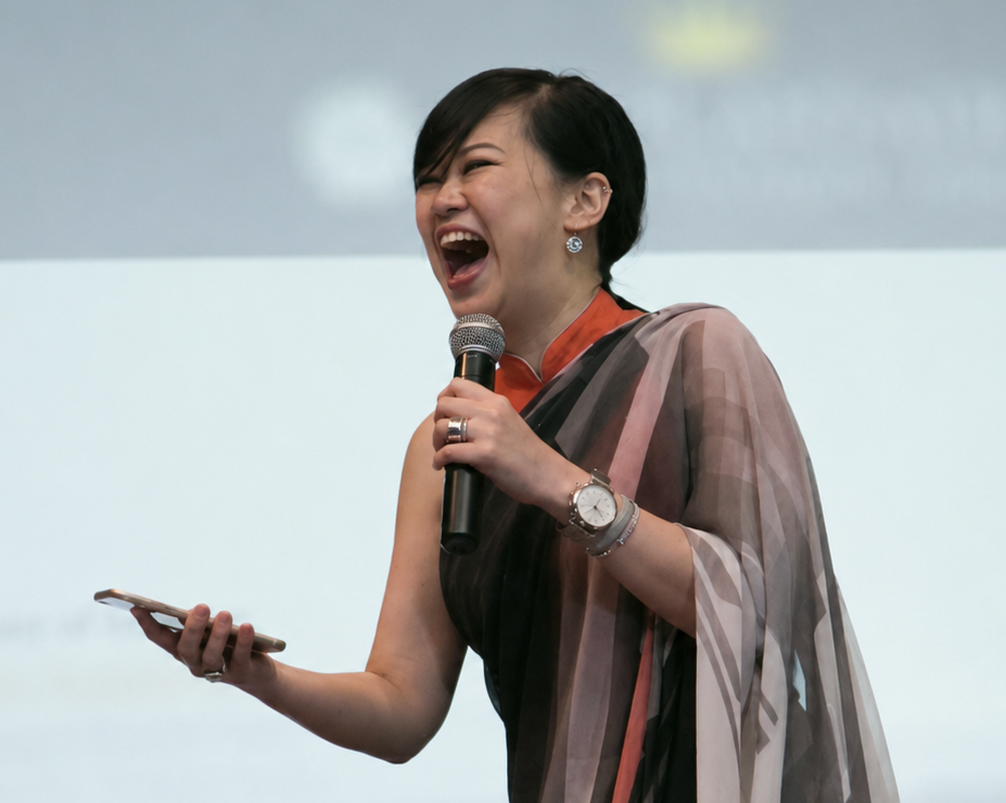 Charlene laughing while speaking into a microphone at an event.