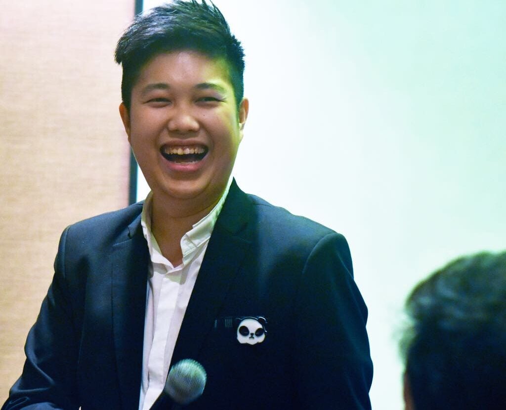 Verrill laughing while holding a microphone at a speaking event.